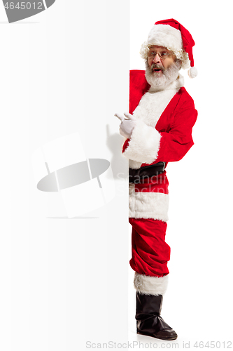 Image of Happy Santa Claus pointing on blank advertisement banner background with copy space. Smiling Santa Claus pointing in white blank sign