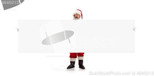 Image of Happy Santa Claus pointing on blank advertisement banner background with copy space. Smiling Santa Claus pointing in white blank sign