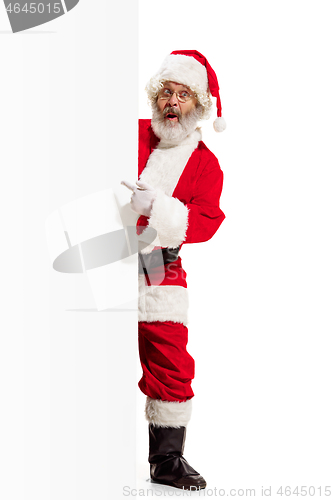 Image of Happy Santa Claus pointing on blank advertisement banner background with copy space. Smiling Santa Claus pointing in white blank sign