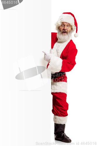 Image of Happy Santa Claus pointing on blank advertisement banner background with copy space. Smiling Santa Claus pointing in white blank sign