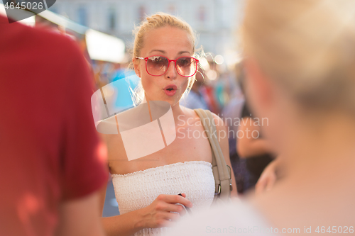 Image of It is nice to see you. It has been a while. Two happy young female friends enjoying a conversation on urban food market at random after work encounter. Pleasant free time socializing