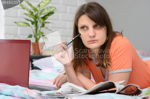 Image of The girl thought while lying in front of a laptop in search of work