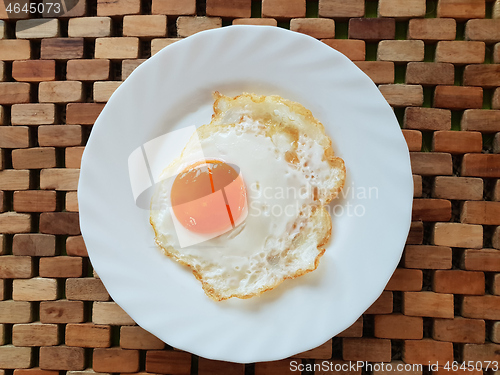 Image of Fried egg on a white plate on a wooden background