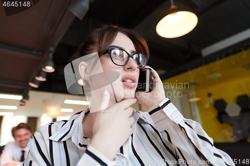 Image of portrait of businesswoman with glasses using mobile phone