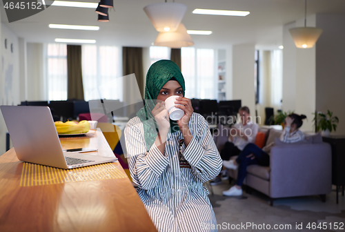 Image of african muslim business woman drinking tea