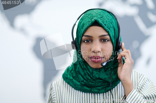 Image of African muslim female with phone headset helping and supporting 