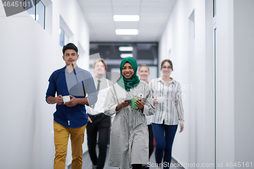 Image of multi-ethnic startup business team walking through the hallway