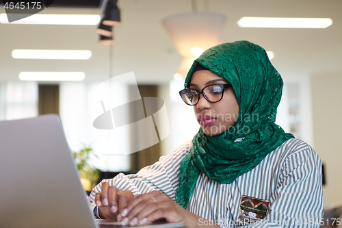 Image of african muslim business woman working on laptop computer