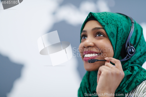 Image of African muslim female with phone headset helping and supporting 