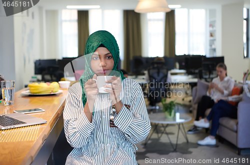 Image of african muslim business woman drinking tea