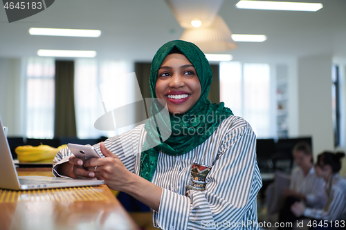 Image of african muslim business woman using mobile phone