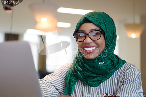 Image of african muslim business woman working on laptop computer