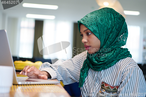 Image of african muslim business woman working on laptop computer