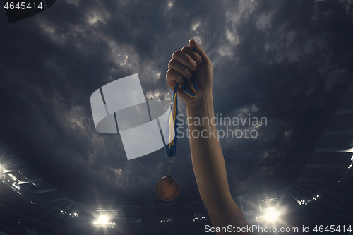 Image of Award of victory, male hands tightening the medal of winners against cloudy dark sky