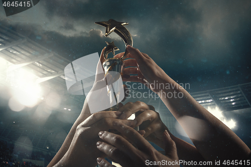 Image of Award of victory, male hands tightening the cup of winners against cloudy dark sky