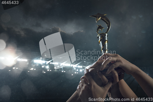 Image of Award of victory, male hands tightening the cup of winners against cloudy dark sky