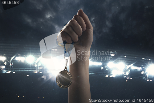 Image of Award of victory, male hands tightening the medal of winners against cloudy dark sky