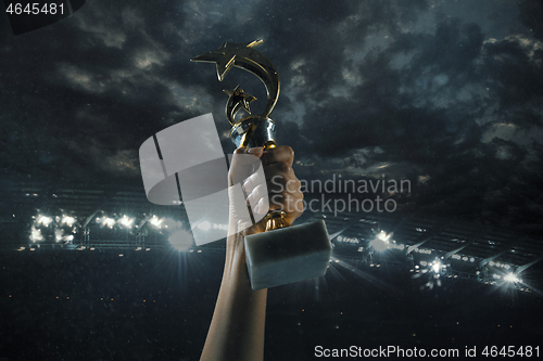 Image of Award of victory, male hands tightening the cup of winners against cloudy dark sky