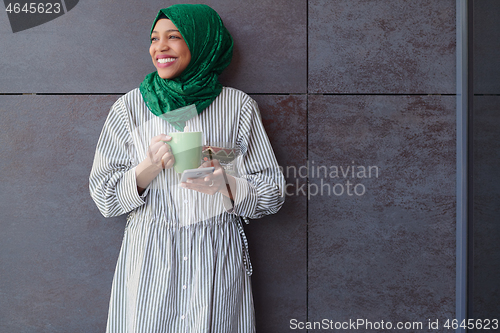Image of african muslim businesswoman with green hijab using mobile phone