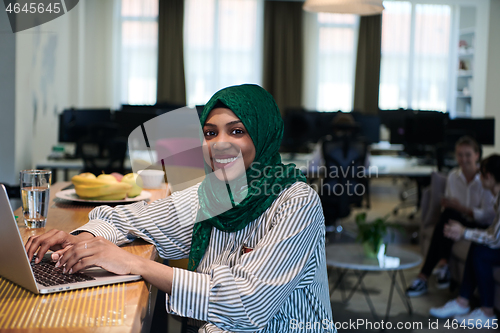 Image of african muslim business woman working on laptop computer