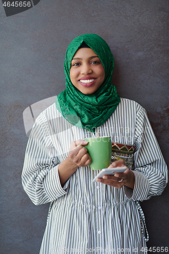 Image of african muslim businesswoman with green hijab using mobile phone