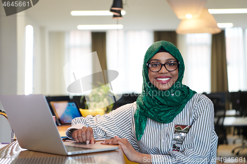 Image of african muslim business woman working on laptop computer