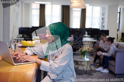 Image of african muslim business woman working on laptop computer