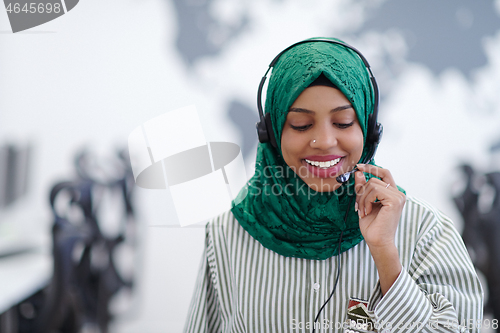 Image of African muslim female with phone headset helping and supporting 