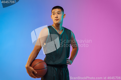 Image of Young basketball player in motion on gradient studio background in neon light