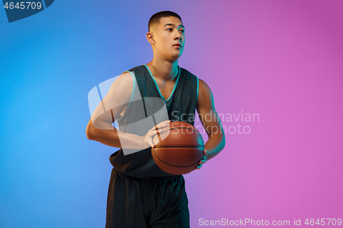 Image of Young basketball player in motion on gradient studio background in neon light