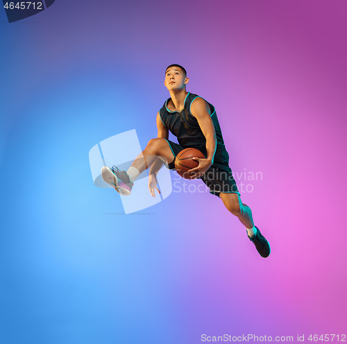 Image of Young basketball player in motion on gradient studio background in neon light