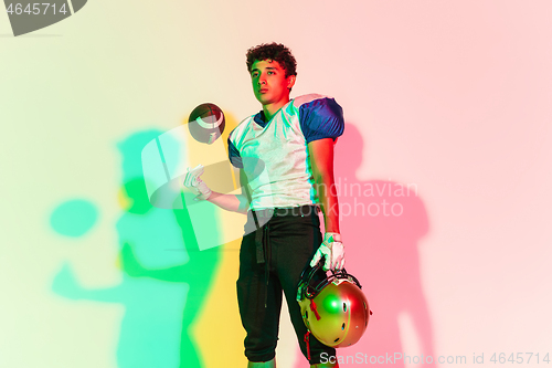 Image of American football player isolated on gradient studio background in neon light with shadows