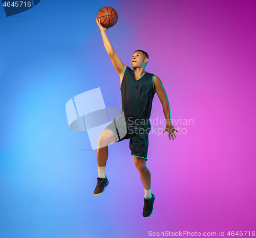 Image of Young basketball player in motion on gradient studio background in neon light