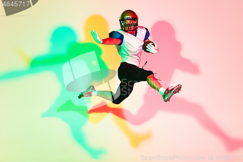 Image of American football player isolated on gradient studio background in neon light with shadows