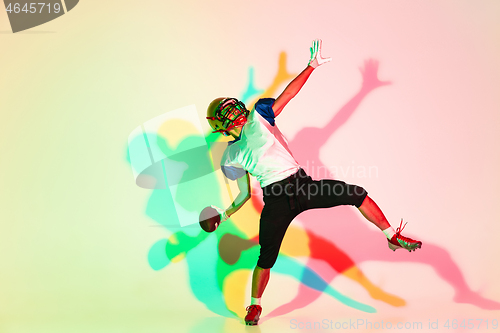 Image of American football player isolated on gradient studio background in neon light with shadows