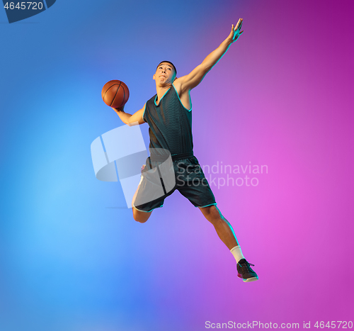 Image of Young basketball player in motion on gradient studio background in neon light