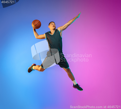 Image of Young basketball player in motion on gradient studio background in neon light