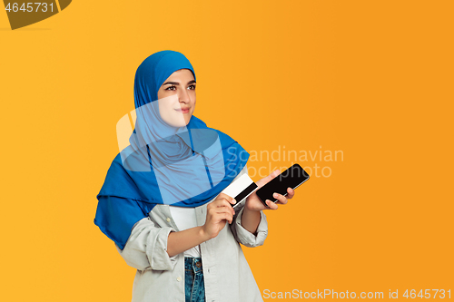 Image of Portrait of young muslim woman isolated on yellow studio background