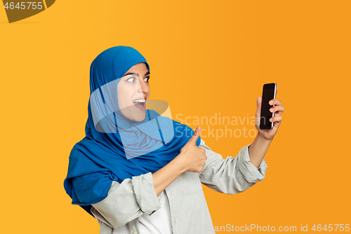 Image of Portrait of young muslim woman isolated on yellow studio background