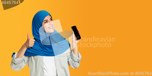 Image of Portrait of young muslim woman isolated on yellow studio background