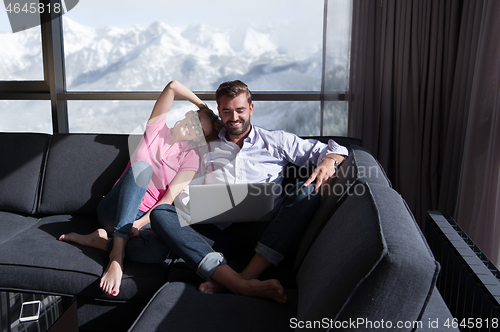 Image of couple relaxing at  home using laptop computers