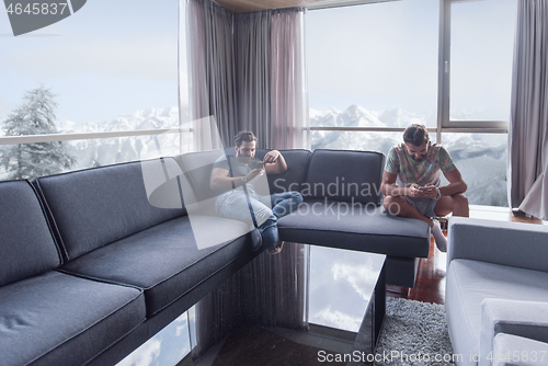 Image of two young men using a mobile phones  at home