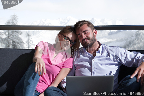 Image of couple relaxing at  home using laptop computers