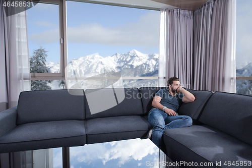 Image of young casual man using a mobile phone at home