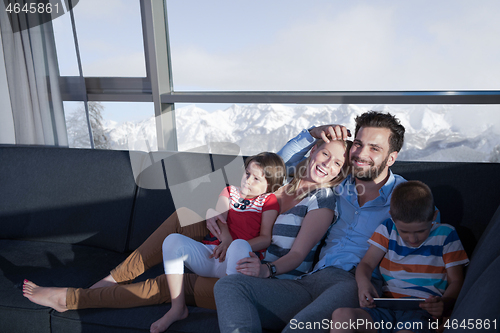 Image of happy young couple spending time with kids at home