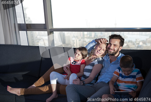 Image of happy young couple spending time with kids at home