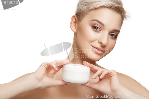 Image of Cute girl preparing to start her day. She is applying moisturizer cream on face.