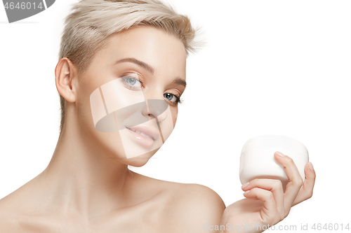 Image of Cute girl preparing to start her day. She is applying moisturizer cream on face.
