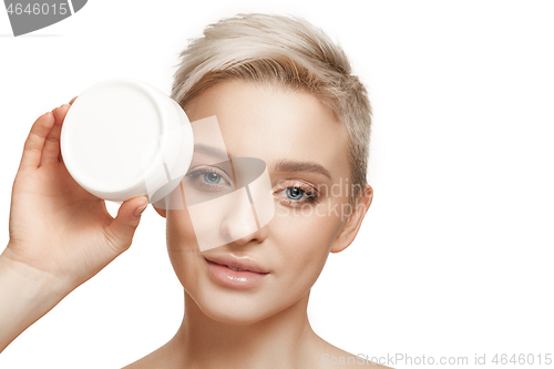 Image of Cute girl preparing to start her day. She is applying moisturizer cream on face.