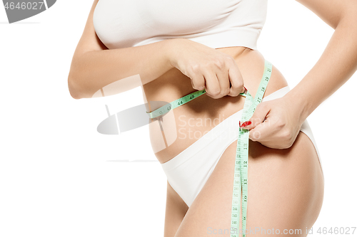 Image of Beauty body care. Woman holding the meter with hands and measuring waist.